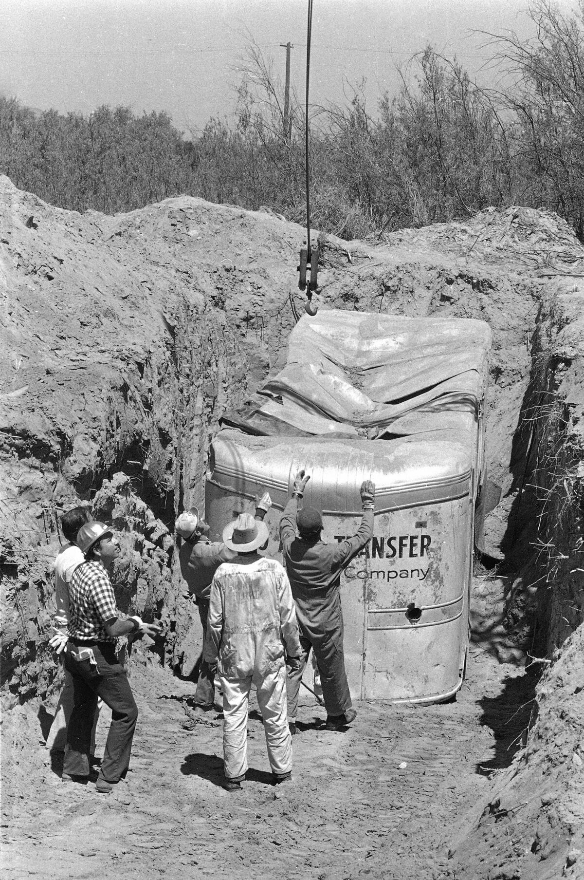 A buried truck trailer is lifted from the earth.