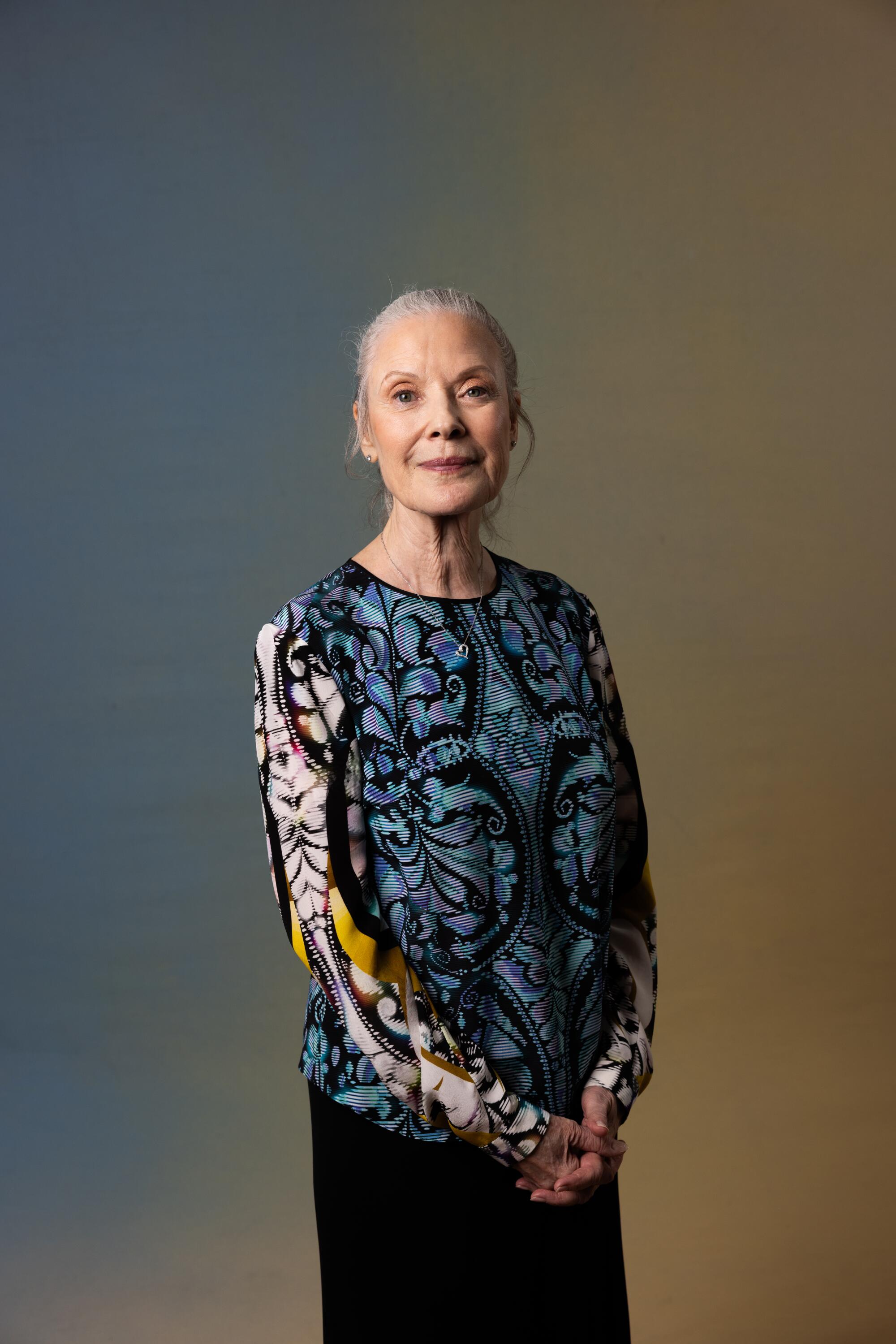 Karen Kaim in a patterned blouse stands and smiles.