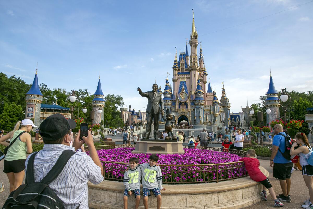 People take photos of people with a statue and castle behind them.