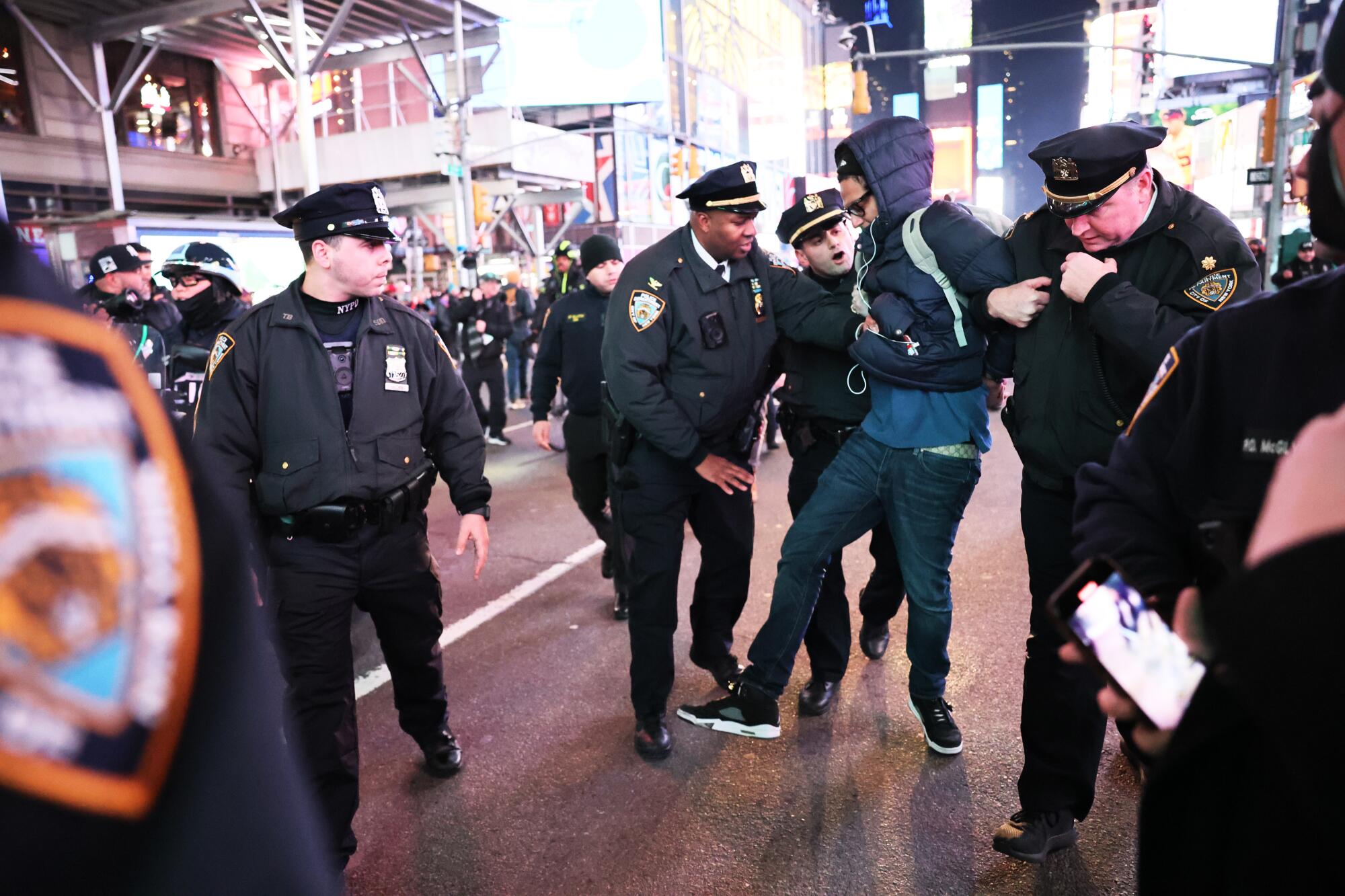 Three police officers restrain a young man on a street in New York.