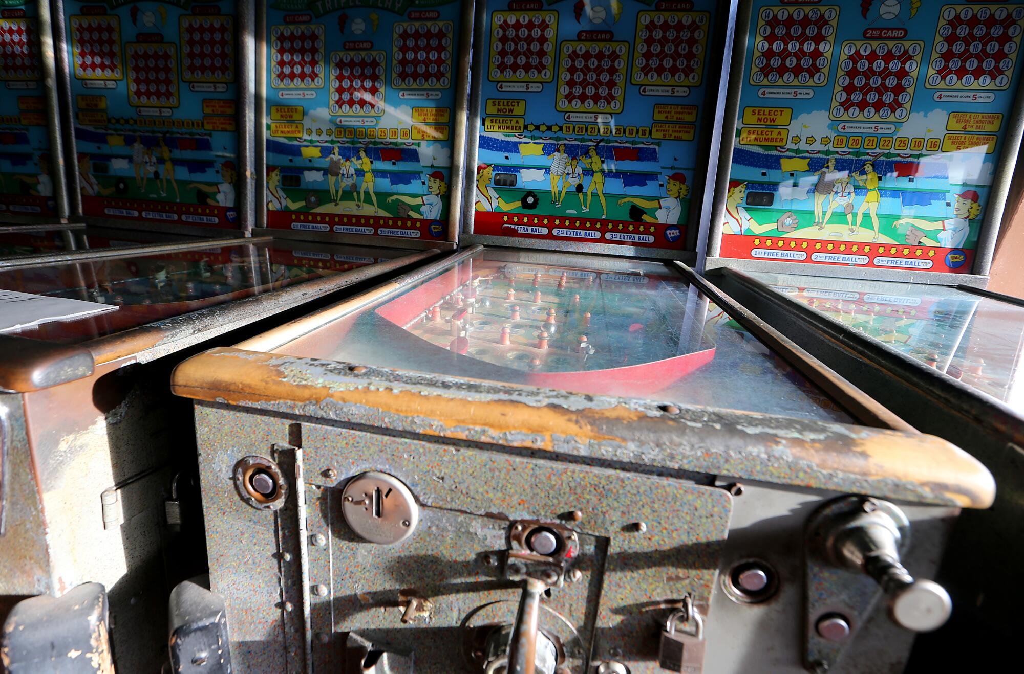 Vintage and weathered pinball machines line a wall.