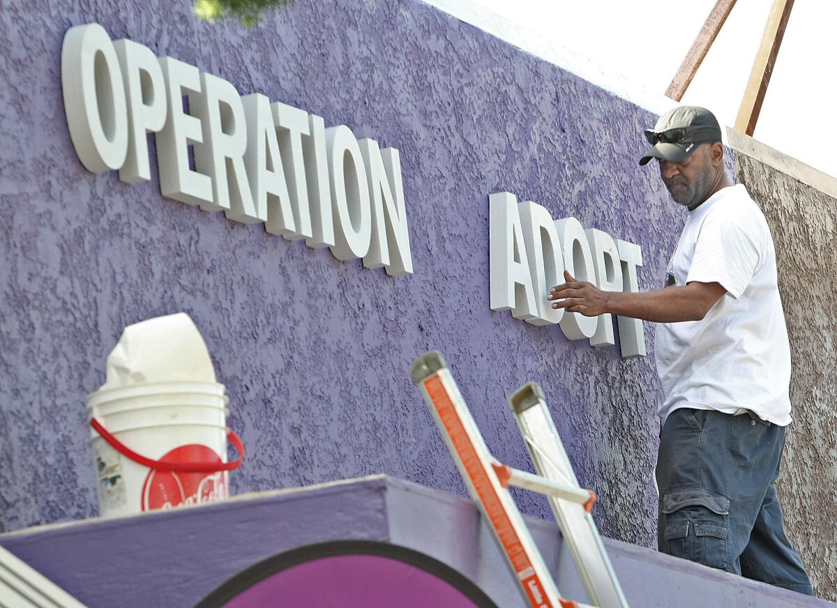 Gerald Mayo from Signs Unlimited installs a new sign for Operation Adopt thanks to some generous donations. Photographed on Monday, September 21, 2015.