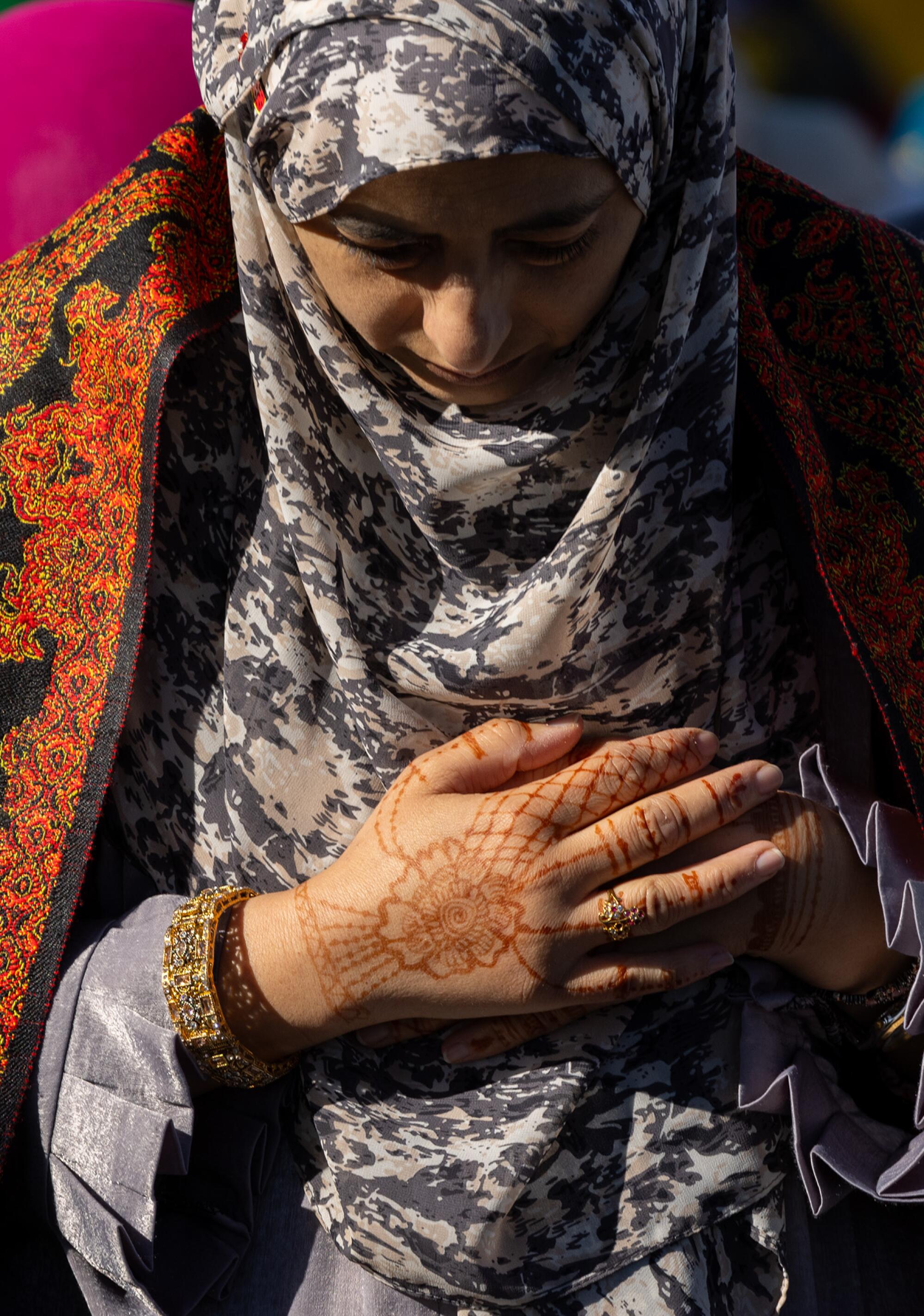 A woman with henna tattoos prays at the Pierce College football stadium in Los Angeles.