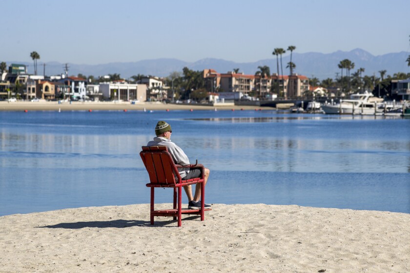 A man enjoys the view of the marina and the mountains from Bayshore Beach in Long Beach.