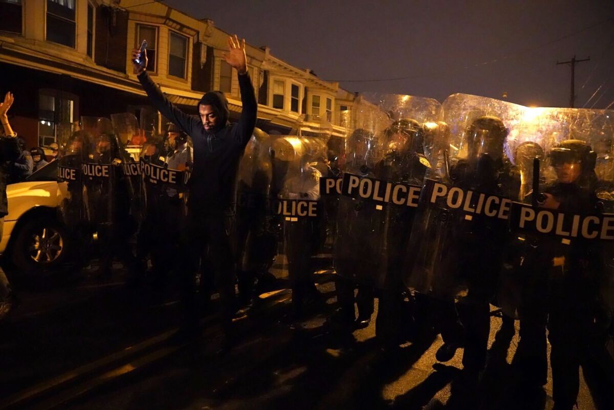 A demonstrator lifts his hands before police during a protest of a fatal police shooting in Philadelphia.