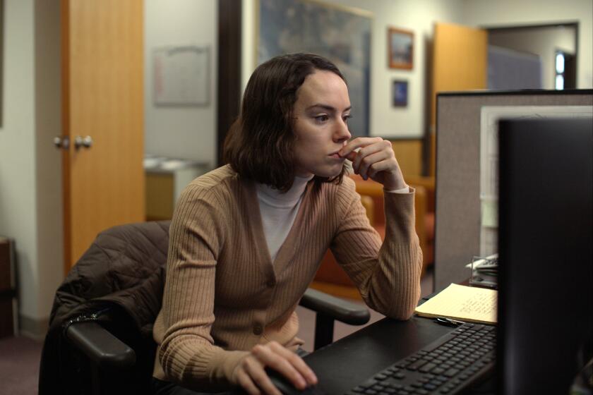 A woman leans over her desk toward her computer