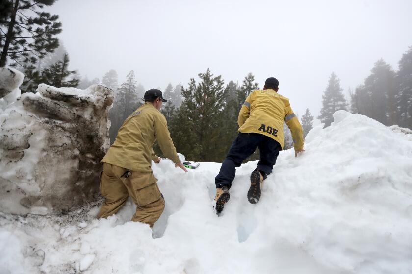 LAKE ARROWHEAD, CA - MARCH 10: Fire line medic Aaron Thomas, left, and medic Mike Age, right, climb a steep snow berm as they attempt to deliver prescription medicine to a snowed-in San Bernardino mountain resident on Friday, March 10, 2023 in Lake Arrowhead, CA. (Brian van der Brug / Los Angeles Times)