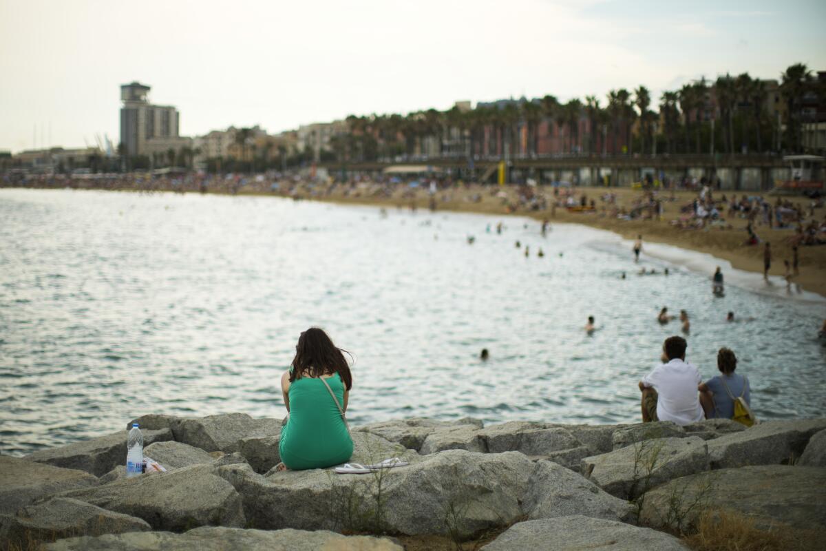 Una mujer está sentada junto a la playa en Barcelona el 28 de julio de 2022. 
