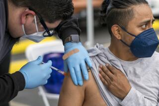 LOS ANGELES, CA - JANUARY 29: Micheal Federico, left, gives Raymundo de Los Santos, 35, right, a vaccinination at the historic First African Methodist Episcopal Church (FAME) on Saturday, Jan. 29, 2022 in Los Angeles, CA. L.A. Care Health Plan has partnered with the historic First African Methodist Episcopal Church (FAME) to offer free COVID-19 vaccines, including first, second and booster doses, as well as COVID-19 testing. The free event is open to the public. (Francine Orr / Los Angeles Times)