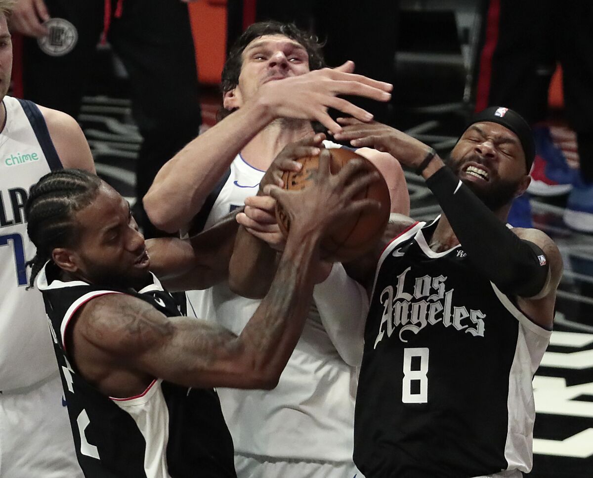 Clippers forwards Marcus Morris Sr. #8 and Kawhi Leonard #2 wrestle the ball from Mavericks center Boban Marjanovic.