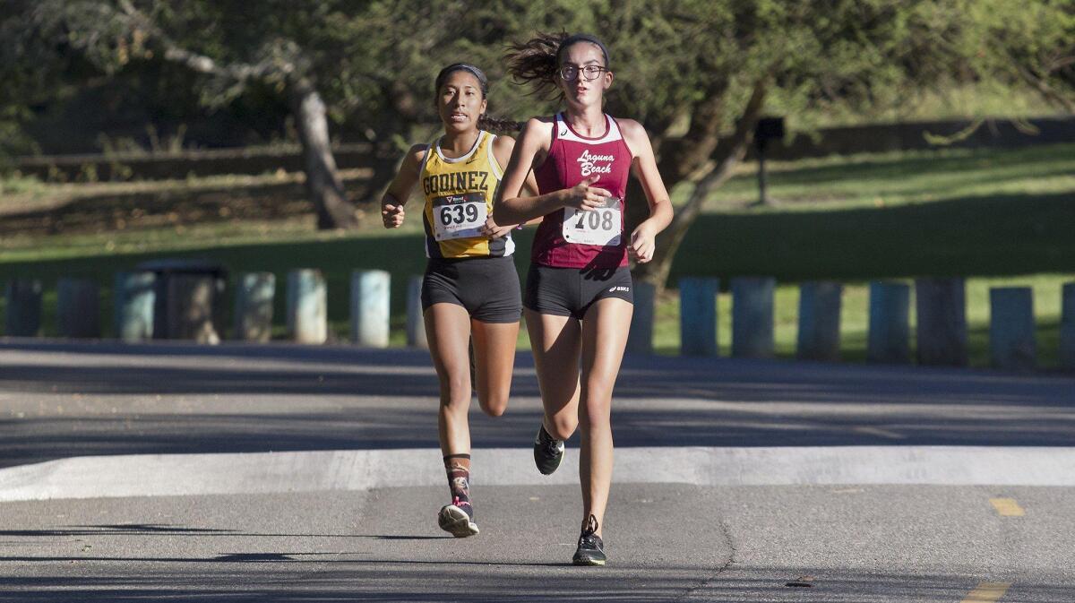 Laguna Beach High’s Ana Kelly, right, leads the varsity girls heat during the Orange Coast League cross country finals at Irvine Regional Park in Orange on Wednesday.
