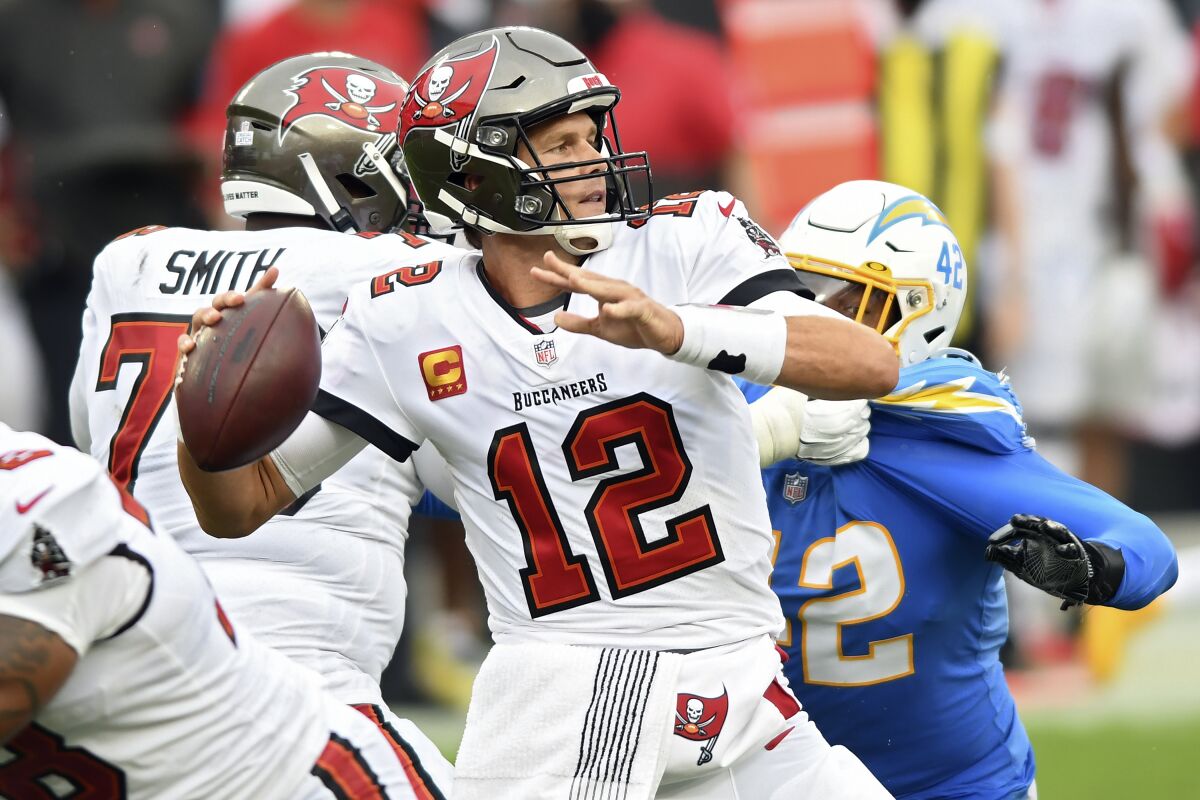 Tampa Bay Buccaneers quarterback Tom Brady (12) eludes Los Angeles Chargers linebacker Uchenna Nwosu (42) as he throws a pass during the first half of an NFL football game Sunday, Oct. 4, 2020, in Tampa, Fla. (AP Photo/Jason Behnken)