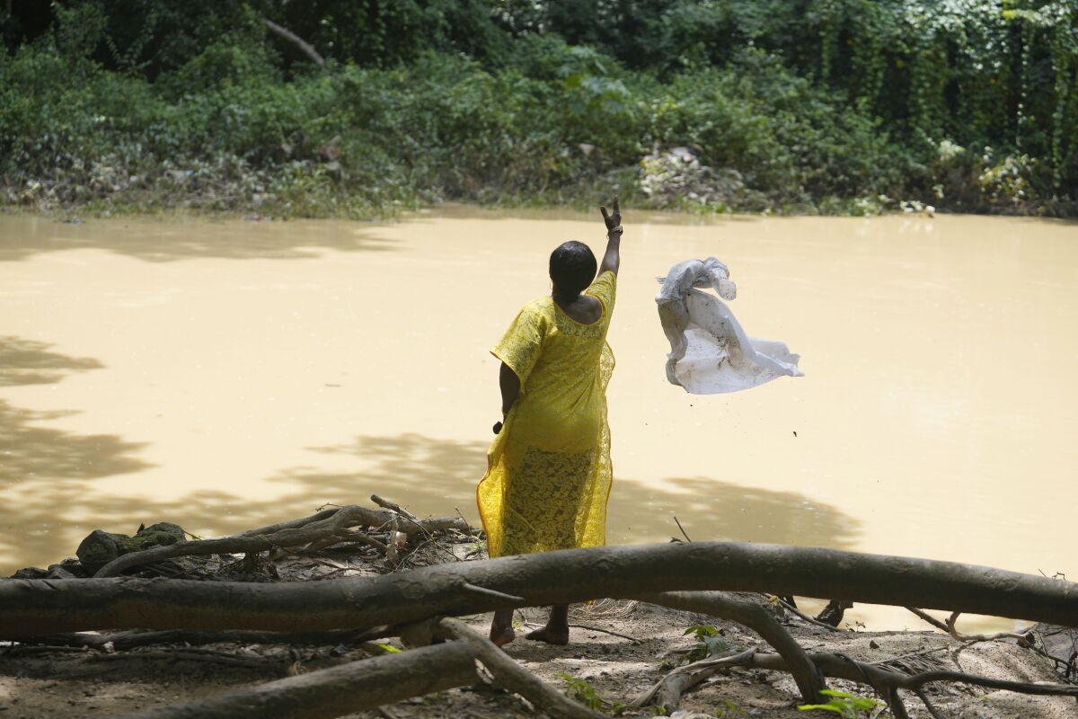 Una devota de la diosa del río Osun arroja a las aguas sagradas una tela blanca utilizada para los sacrificios, en Osogbo, Nigeria, el domingo 29 de mayo de 2022. (Foto AP/Sunday Alamba)