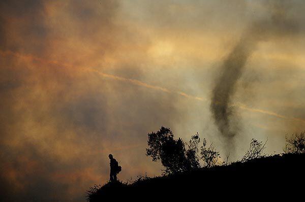 A U.S. Forest Service firefighter monitors the Station fire as smoke spins behind him on a ridge along Angeles Crest Highway in La Ca?ada Flintridge.