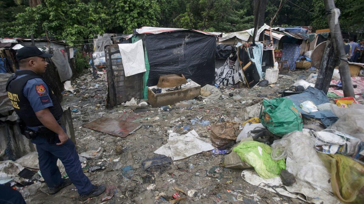 A policeman guards an alleged drug den after a raid in which two drug suspects were killed and about 90 people arrested in Quezon City on Oct. 5, 2016, less than two months after Cherwen Polo was shot and killed by Philippine police.