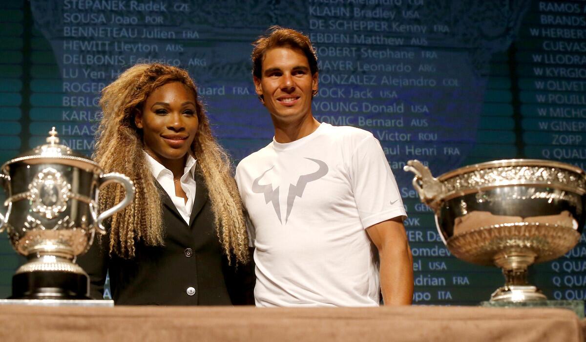 Defending French Open champions Serena Williams and Rafael Nadal pose next to the women's and men's trophies on Friday in Paris.