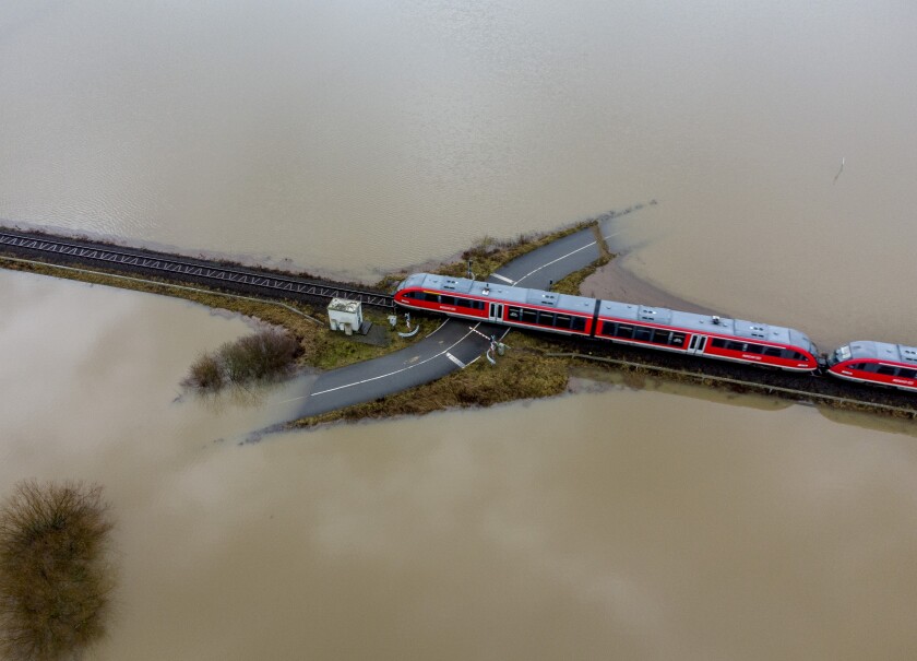 A train passes a railroad crossing surrounded by floodwaters from rain and melting snow in Nidderau near Frankfurt, Germany, on Feb. 3, 2021. (AP Photo/Michael Probst)