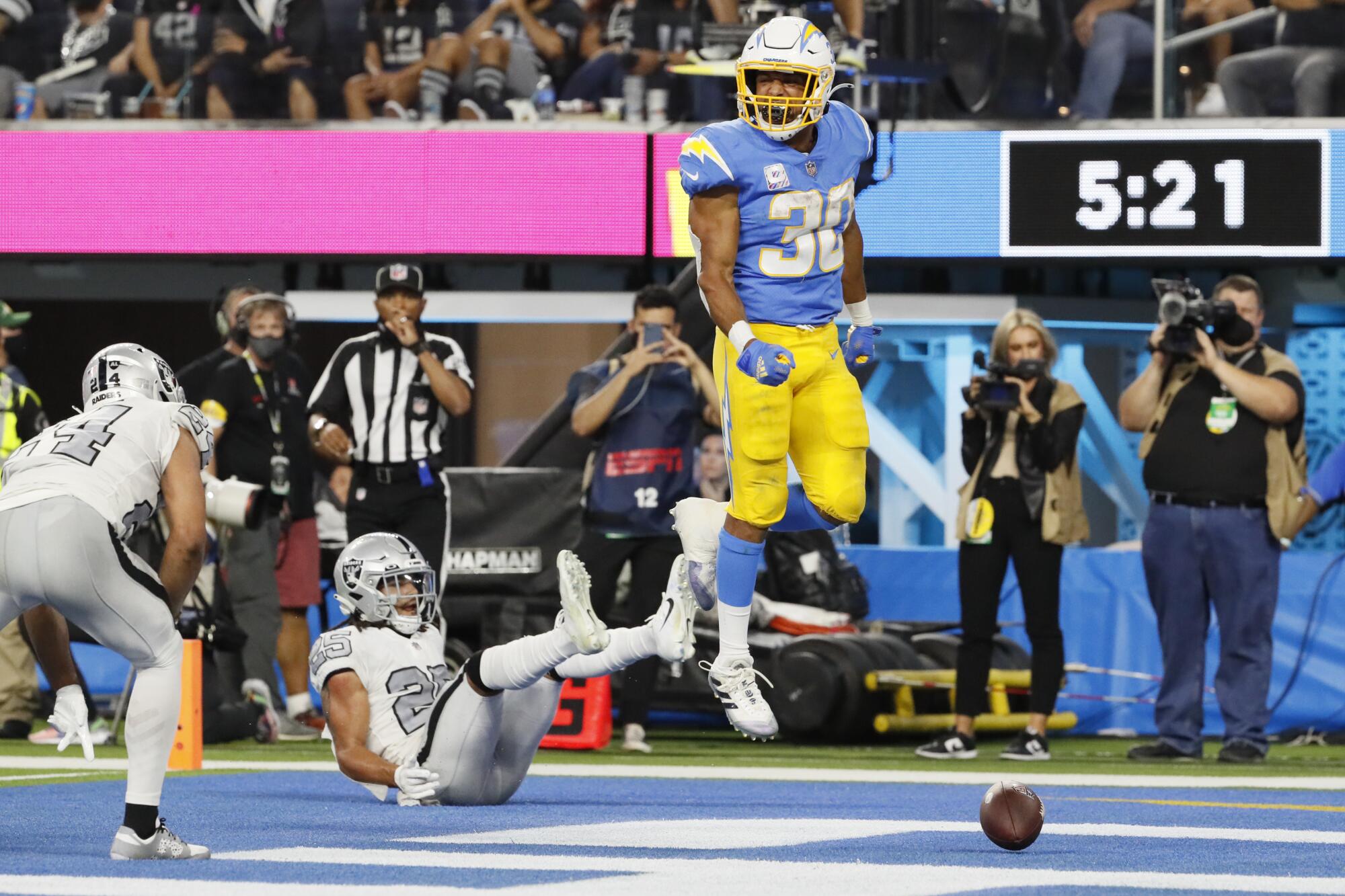 Los Angeles Chargers running back Austin Ekeler scores a touchdown past Las Vegas Raiders safety Trevon Moehrig