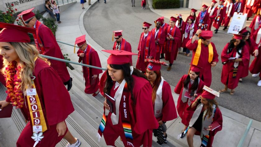 Students graduating at Pasadena City College in June. A strong job market should encourage students to finish early or defer education in favor of employment, leading to sliding enrollment. That hasn't happened to any great extent.