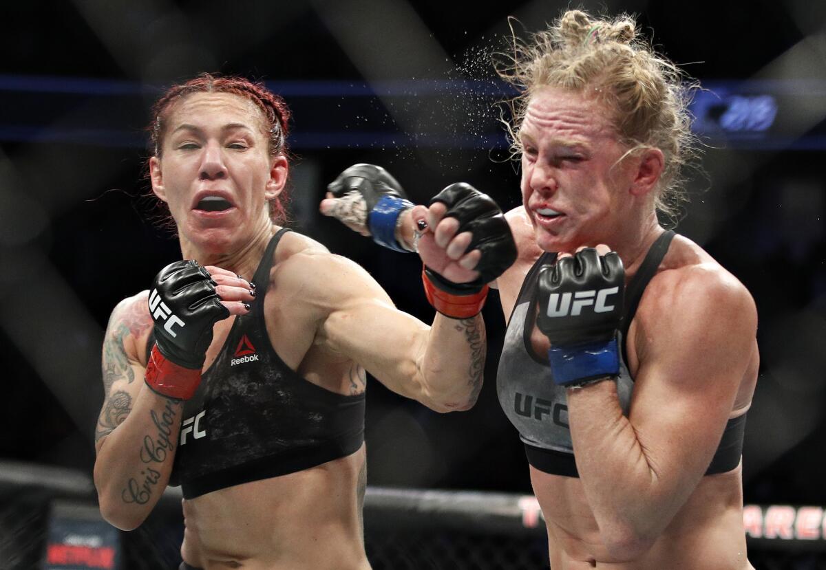 Cris Cyborg hits Holly Holm during a featherweight championship mixed martial arts bout at UFC 219.