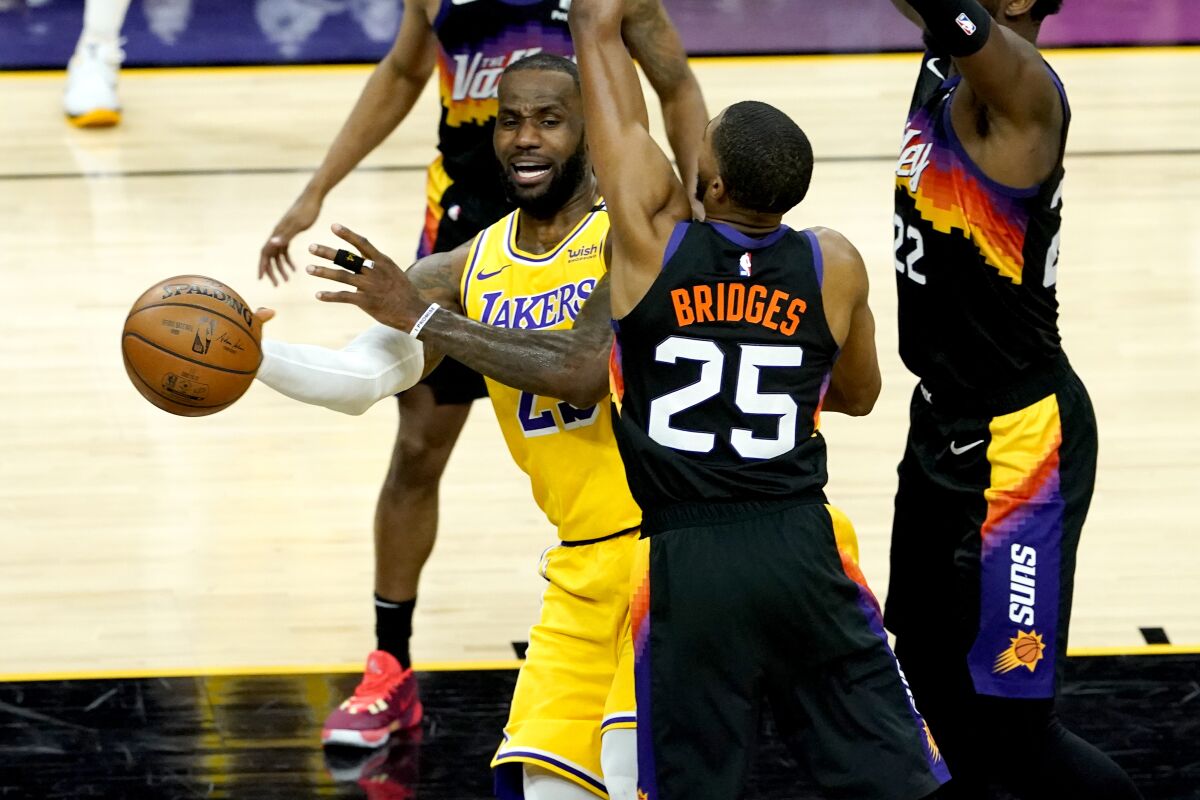 Los Angeles Lakers forward LeBron James passes around Phoenix Suns forward Mikal Bridges 