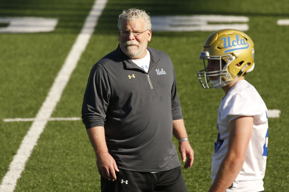 UCLA defensive coordinator Jerry Azzinaro stands on the field with a player.