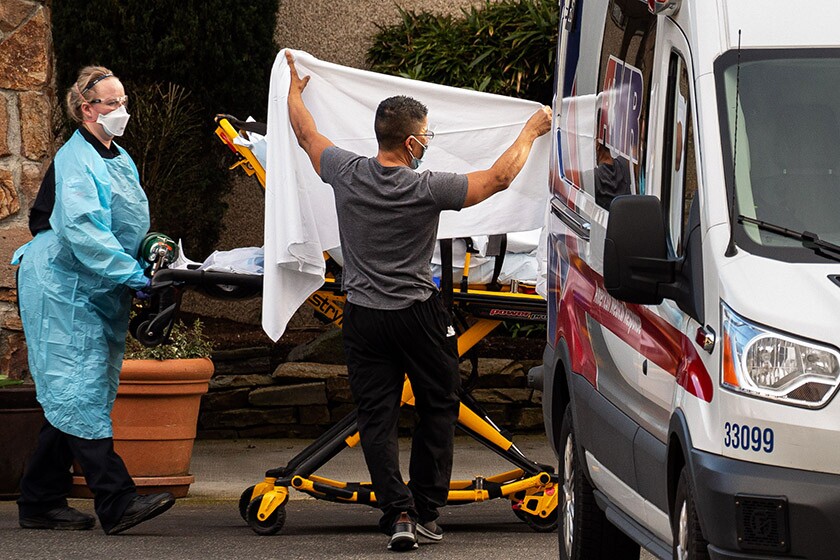 Workers load a patient into an ambulance at Life Care Center of Kirkland.