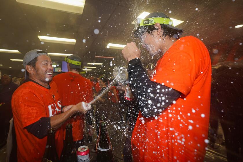 Baltimore Orioles relief pitcher Shintaro Fujinami, right, is doused by his translator Issei Kamada while celebrating the Orioles' AL East championship following a 2-0 victory over the Boston Red Sox in a baseball game, Thursday, Sept. 28, 2023, in Baltimore. (AP Photo/Julio Cortez)