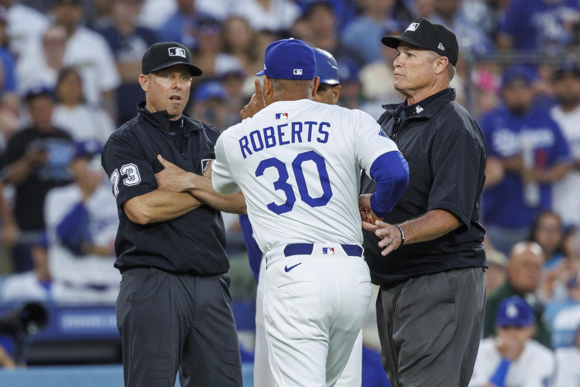 El gerente de los Dodgers, Dave Roberts, señala el árbitro de la tercera base Tripp Gibson, a la izquierda, después de ser expulsado en la tercera entrada el martes.