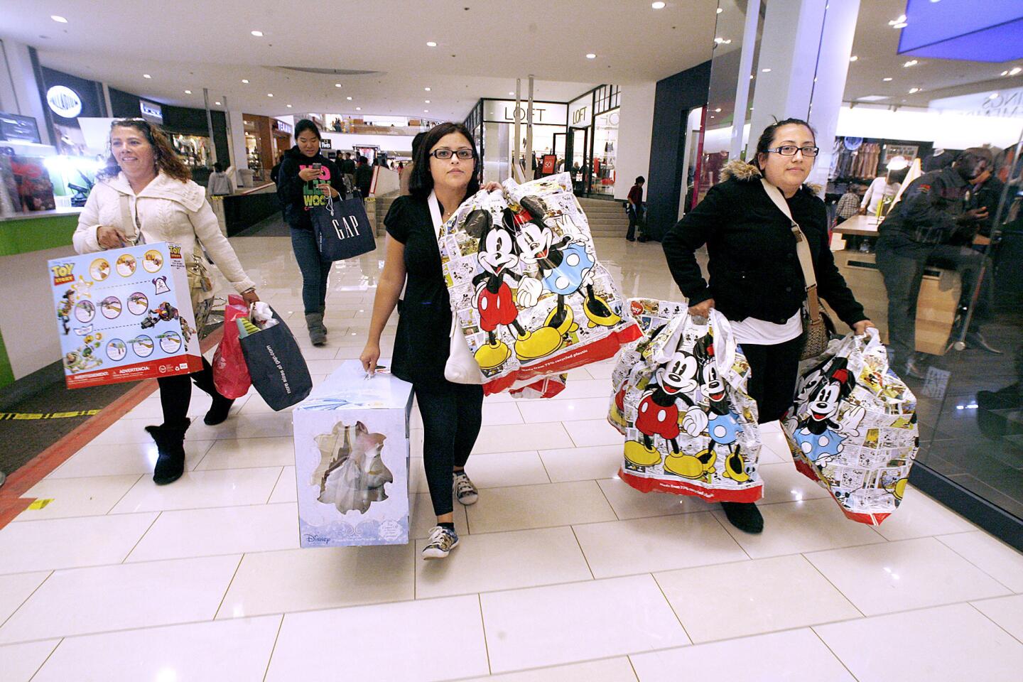 From left, Maria Quintero, of Glendale, Lisette Uribe of Glendale and Elsy Quintero of L.A., carry loads of bags from a shopping spree at the Glendale Galleria in Glendale on Black Friday, Nov. 23, 2012.