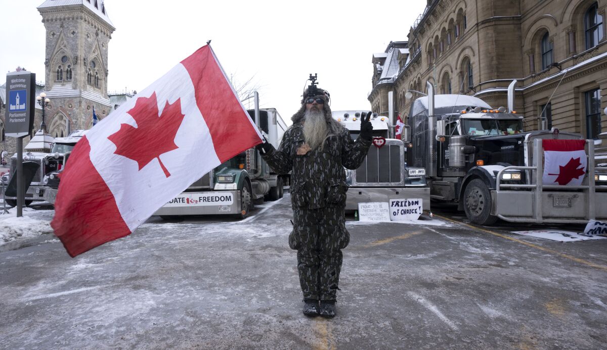 A protester stands in front of vehicles parked in the downtown core, Thursday, Feb. 3, 2022 in Ottawa. Thousands of protesters railing against vaccine mandates and other COVID-19 pandemic restrictions descended on the capital over the weekend, deliberately blocking traffic around Parliament Hill.(Adrian Wyld /The Canadian Press via AP)