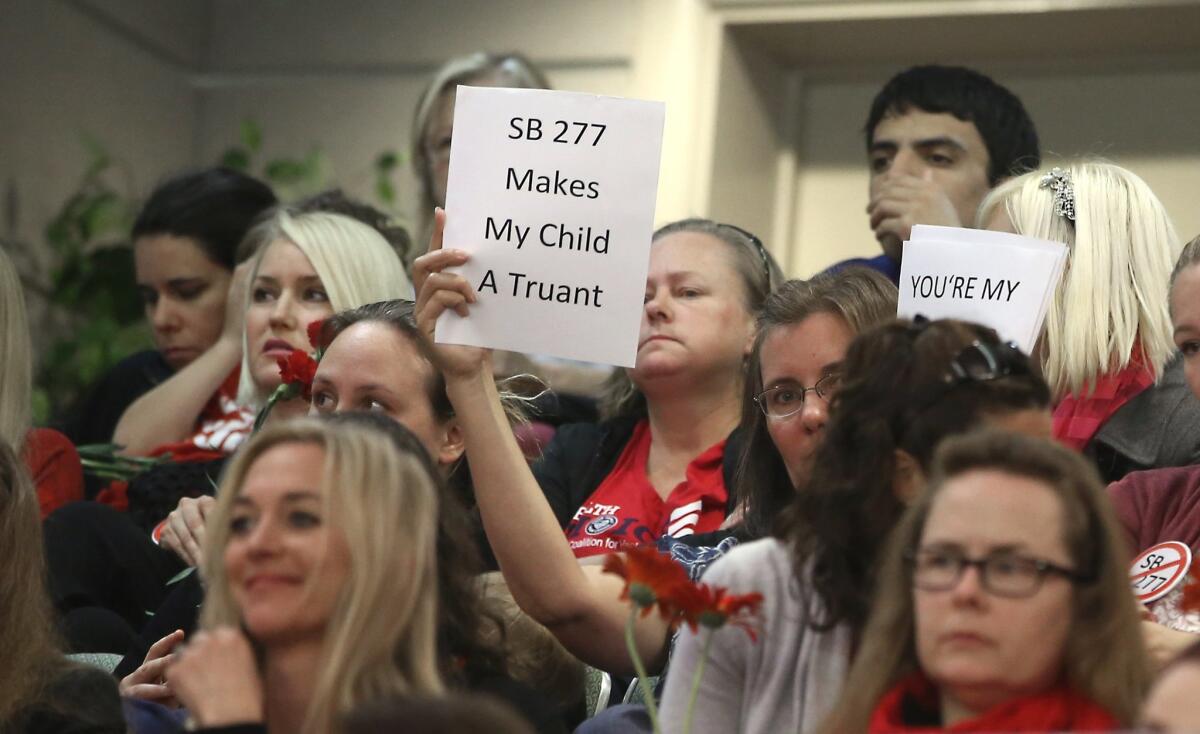 An audience member holds a sign expressing opposition to SB 277, which would end personal-belief exemptions from California's vaccination mandate for schoolchildren, as lawmakers discuss the bill at the Capitol last month.
