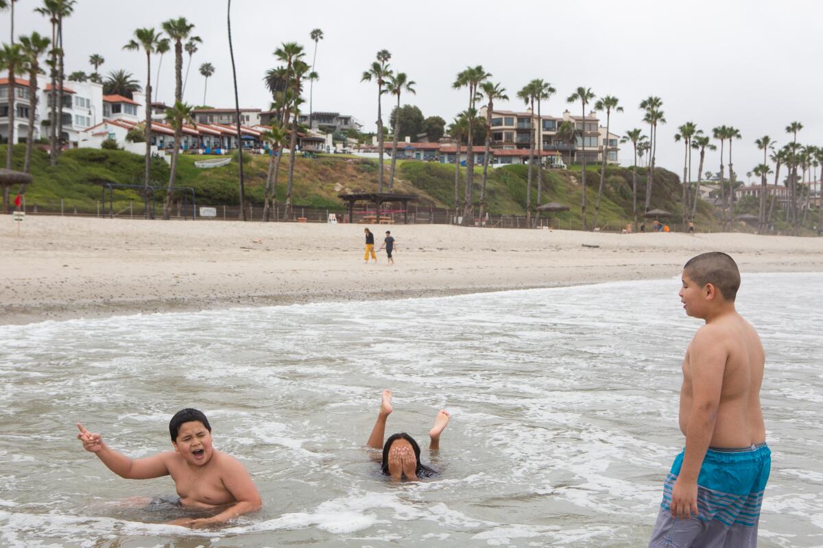 From left, Bryan Lucero, 10, Jocelyn Corado, 8, and Nery Gonzales, 11, play in the surf near the San Clemente Pier.