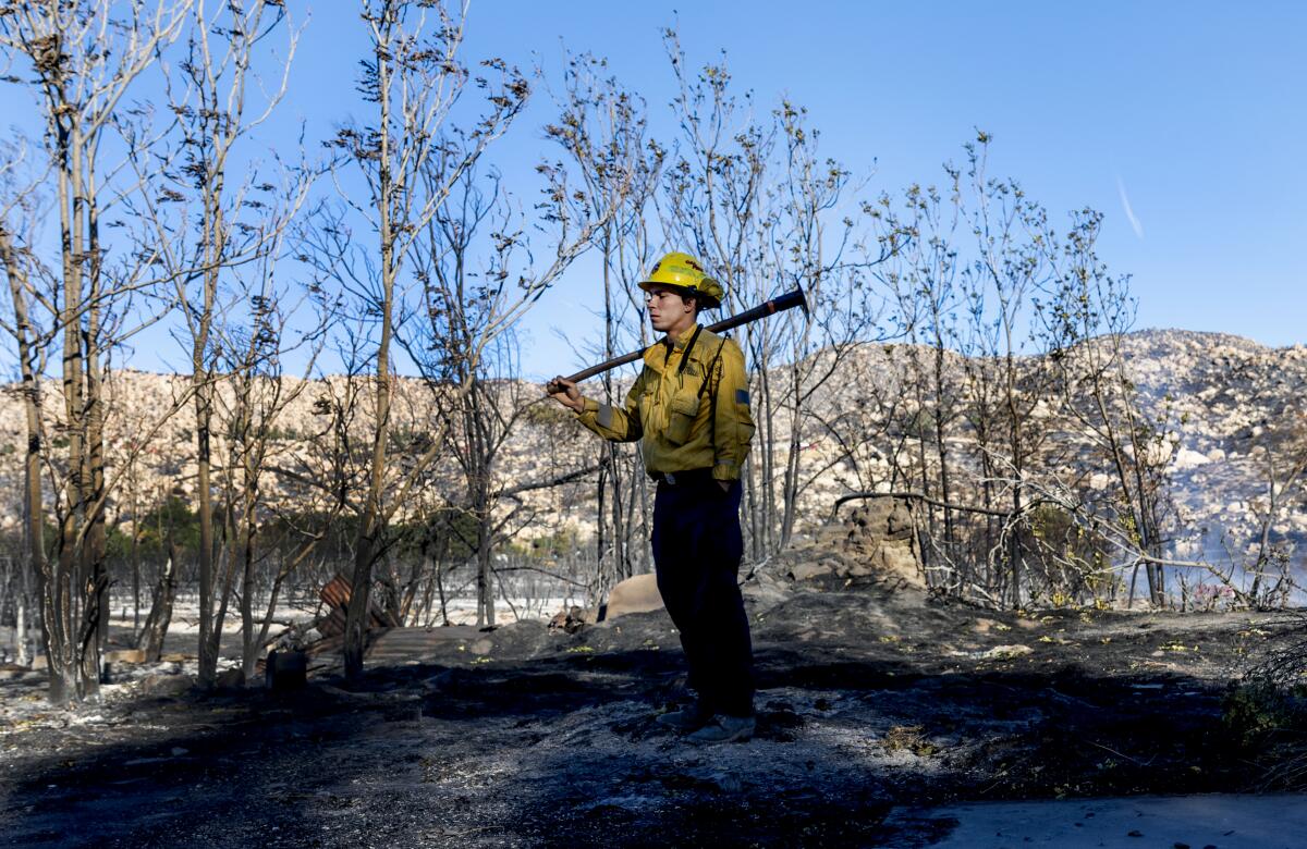 A firefighter waits for crew members to bring water to douse hotspots after the Highland fire in October 2023.