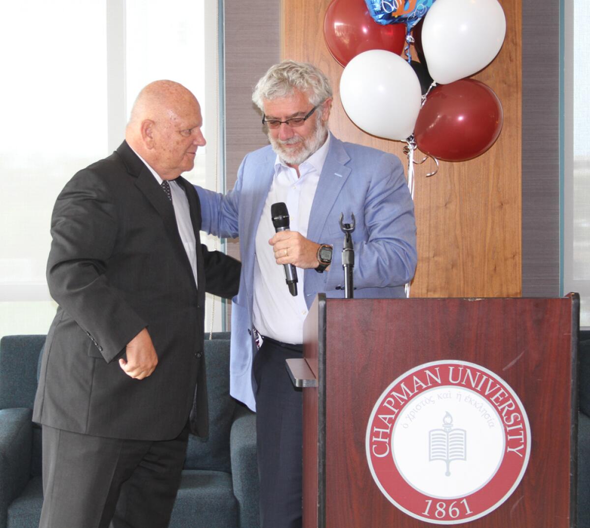 Chapman University president Daniele Struppa stands next to Dave Currey near a podium.