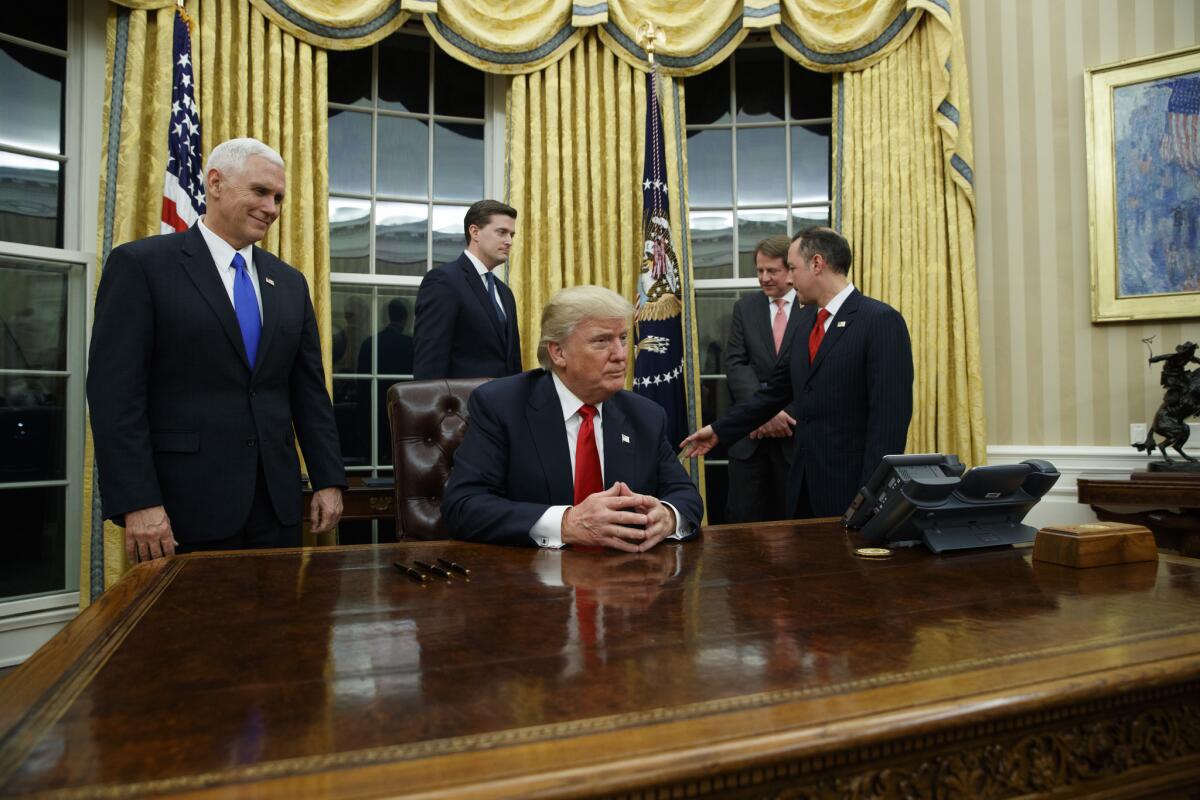 President Donald Trump prepares to sign his first executive order in the newly refurbished Oval Office, where the curtains have been switched from red to gold.