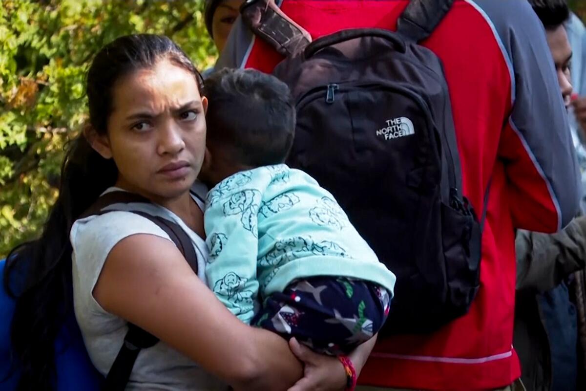 A migrant woman and child standing in a line 