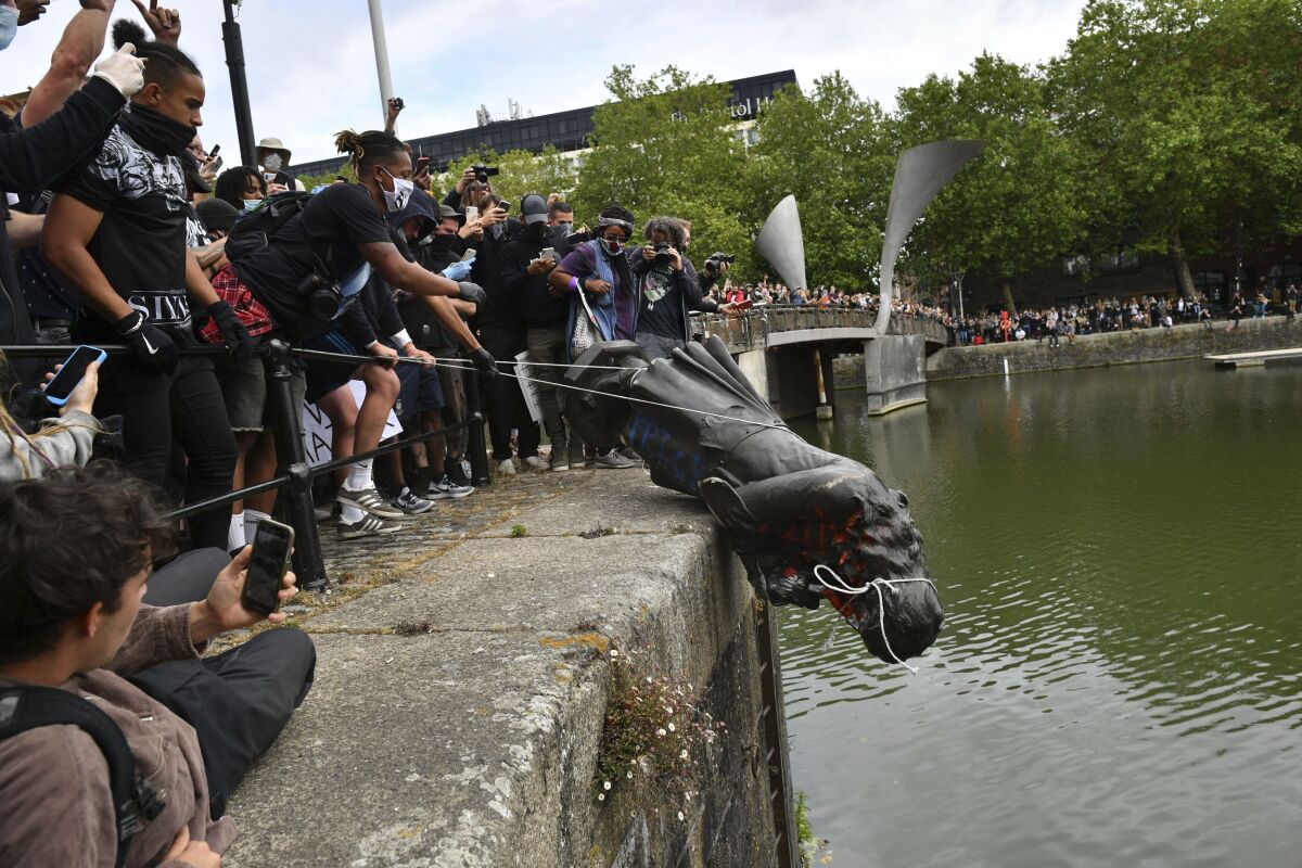 FILE - Protesters throw a statue of Edward Colston into the Bristol harbour during a Black Lives Matter protest rally, Bristol, England, June 7, 2020. Four anti-racism demonstrators were cleared Wednesday Jan. 5, 2022, of criminal damage in the toppling of a statue of a 17th century slave trader during a Black Lives Matter protest in southwestern England 18 months ago. (Ben Birchall/PA via AP, File)