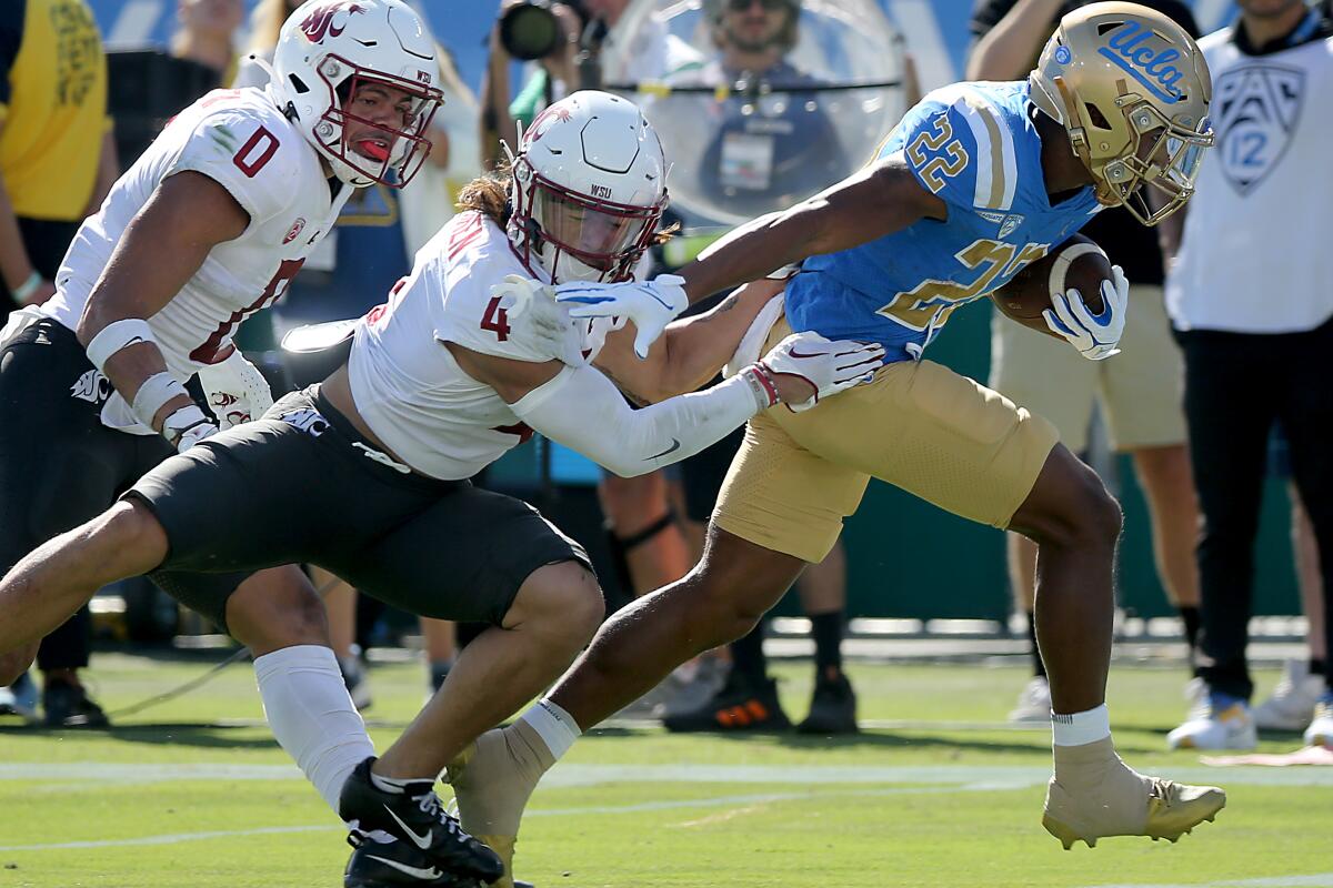 UCLA geri koşuyor Anthony Adkins, Washington Eyaleti defans oyuncusu Kapena Gushiken'in mücadelesini bozuyor.