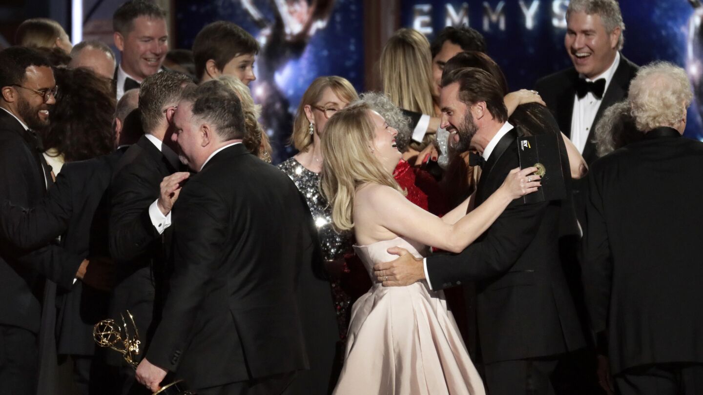 Elisabeth Moss hugs co-star Joseph Fiennes along with the cast of "The Handmaid's Tale" after they won the drama series award during the 69th Emmy Awards at the Microsoft Theater in Los Angeles.