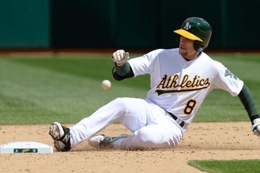 Oakland Athletics shortstop Jed Lowrie slides into second base after doubling against the Cleveland Indians.