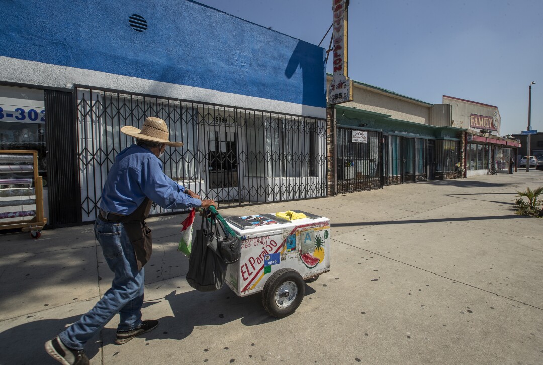  Ice cream vendor Miguel Savala Villa walks past closed businesses on Whittier Blvd. 