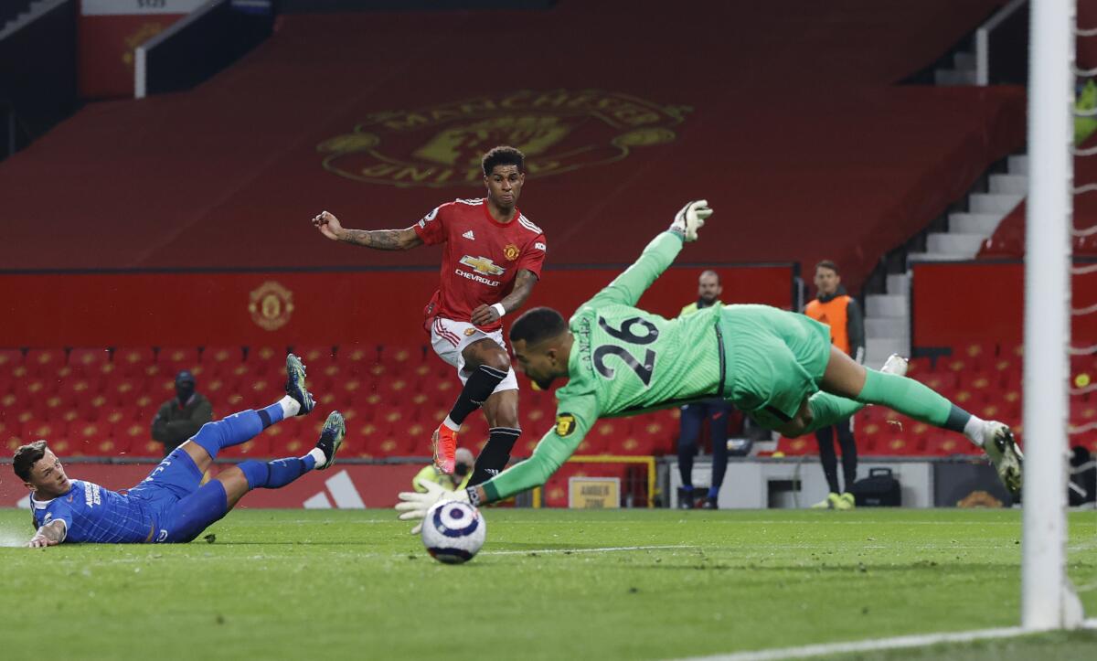 Manchester United's Marcus Rashford, centre, scores his side's opening goal during the English Premier League soccer match between Manchester United and Brighton and Hove Albion at Old Trafford, Manchester, England, Sunday, Apr. 4, 2021. (Phil Noble/Pool via AP)