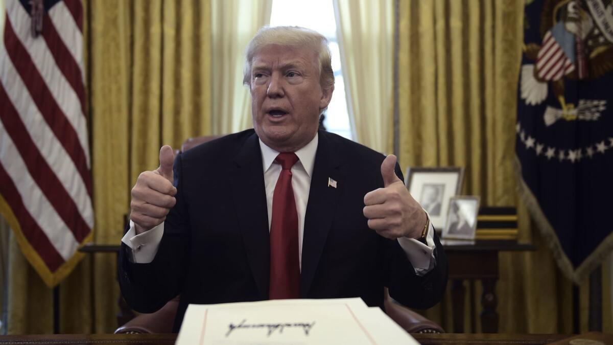 President Trump signals his happiness with the GOP tax cut when signing the measure in December 2017.