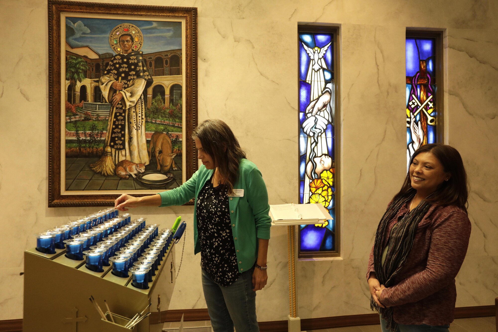 Elena Zuniga lights a candle as Cherie Ibanez looks on at St. Martin de Porres Church in Yorba Linda. 