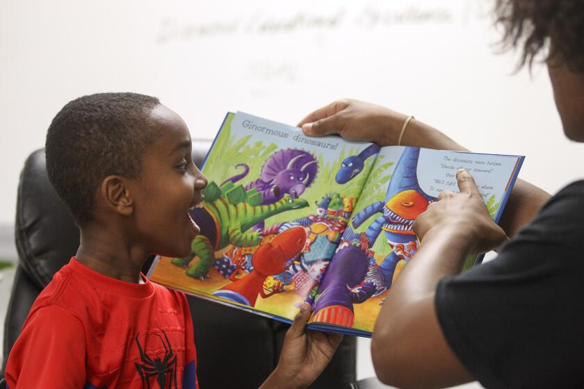 Ahmed Hassan, 7, reacts as he and Jerry Riggings Jr. 16, son of the the owner of Urban Barber College, read "Aliens Love Dinopants" to children during the Summer Time is Reading Time in the Diamond, a children's book read-aloud, at Urban Barber College on Wednesday, July 10, 2019 in San Diego, California.