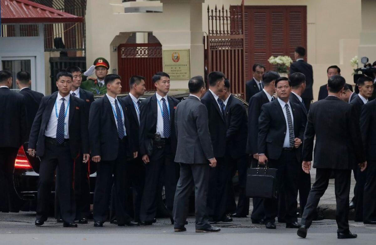 Bodyguards of North Korean leader Kim Jong Un surround his car as it arrives for a visit to the North Korean Embassy in Hanoi.