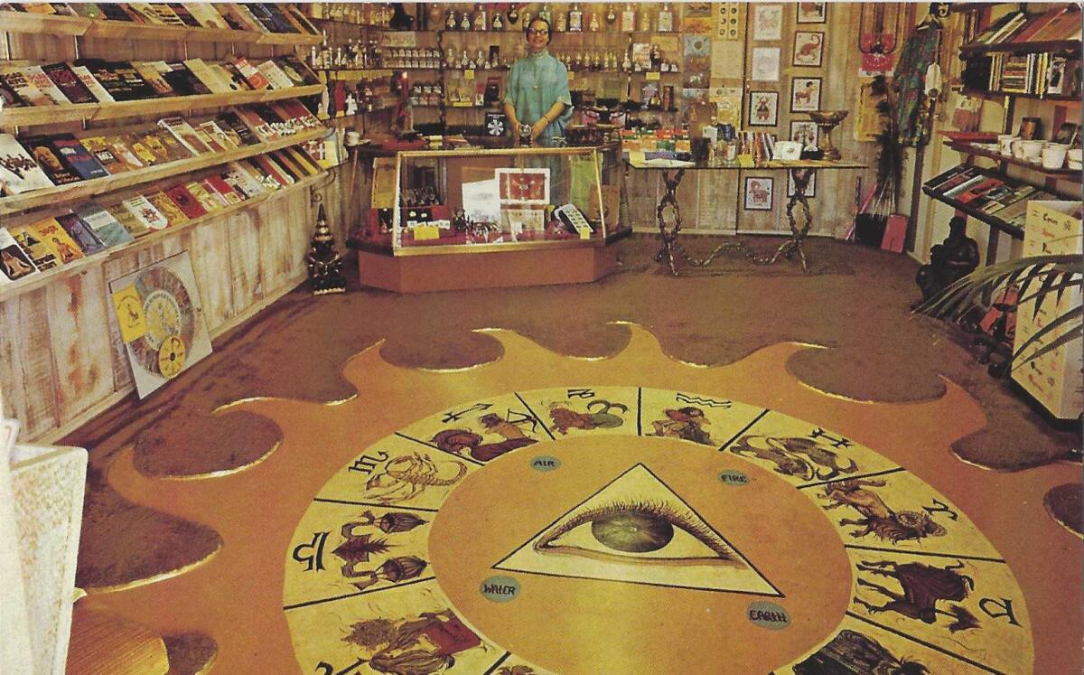 A clerk stands at the back of a bookstore, with a large astrological motif on the floor in the foreground.