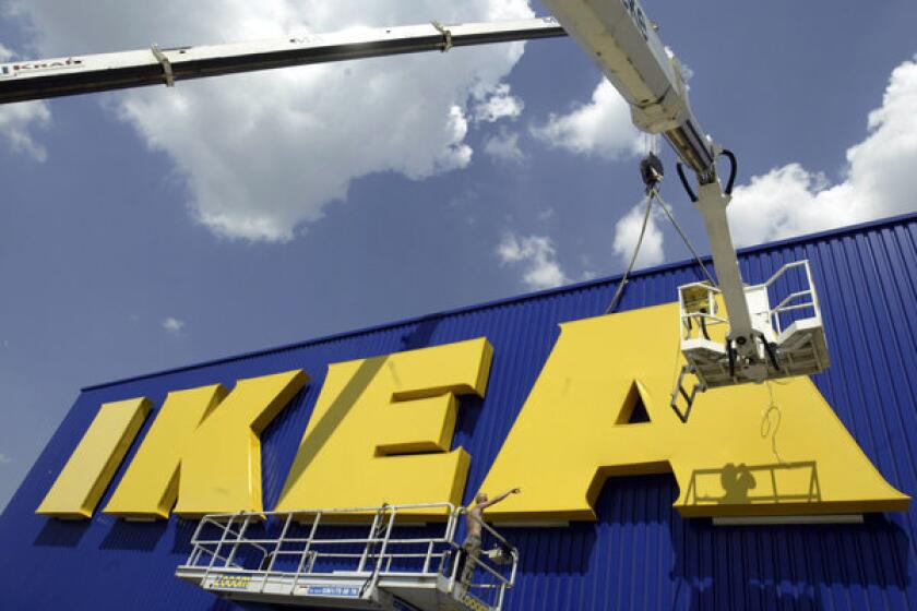 Workers affix the Ikea logo to a new store in eastern Germany. Ikea published a report showing that the company benefited from forced labor in communist East Germany.