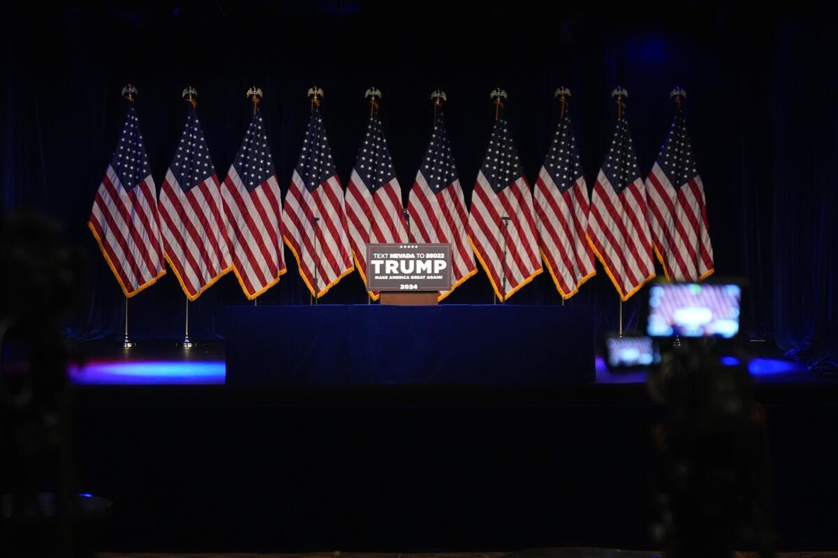 A stage with flags and a lectern that says "Trump"